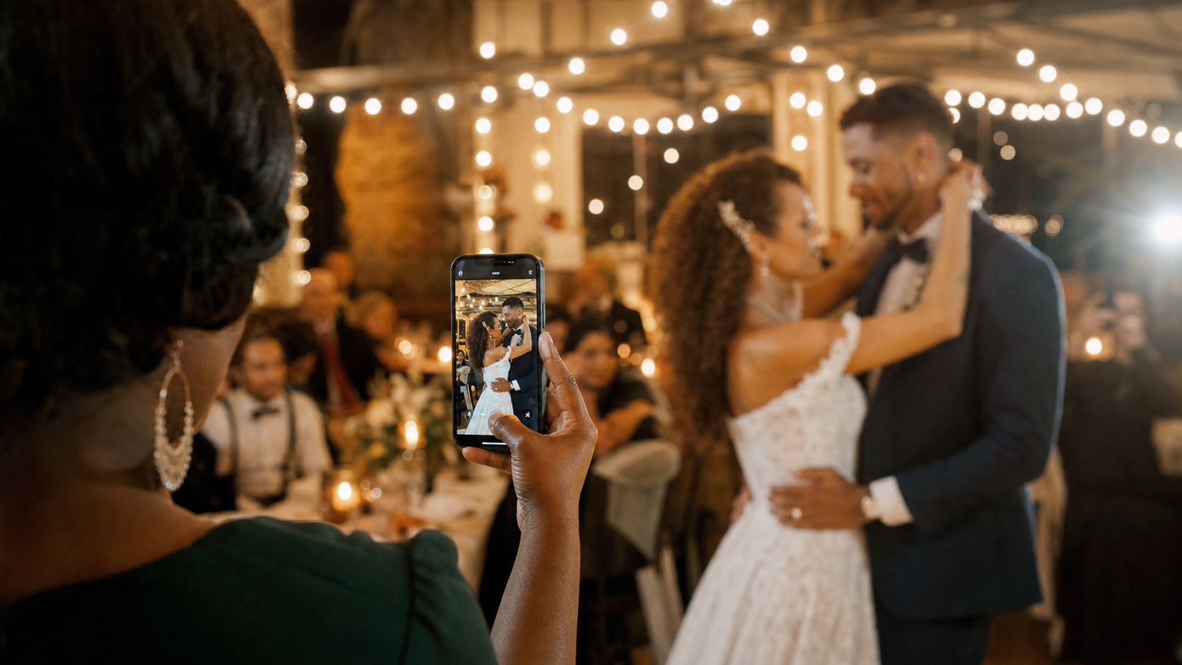 A guest capturing a couple's first dance on a phone
