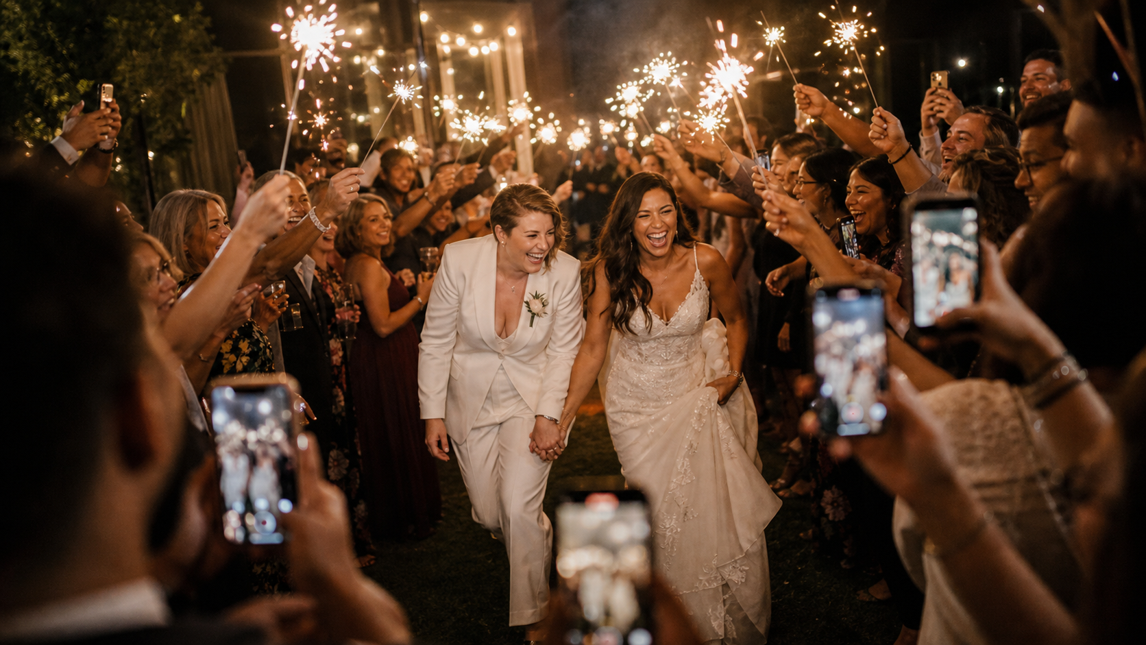 Wedding guests filming a sparkler sendoff around the couple